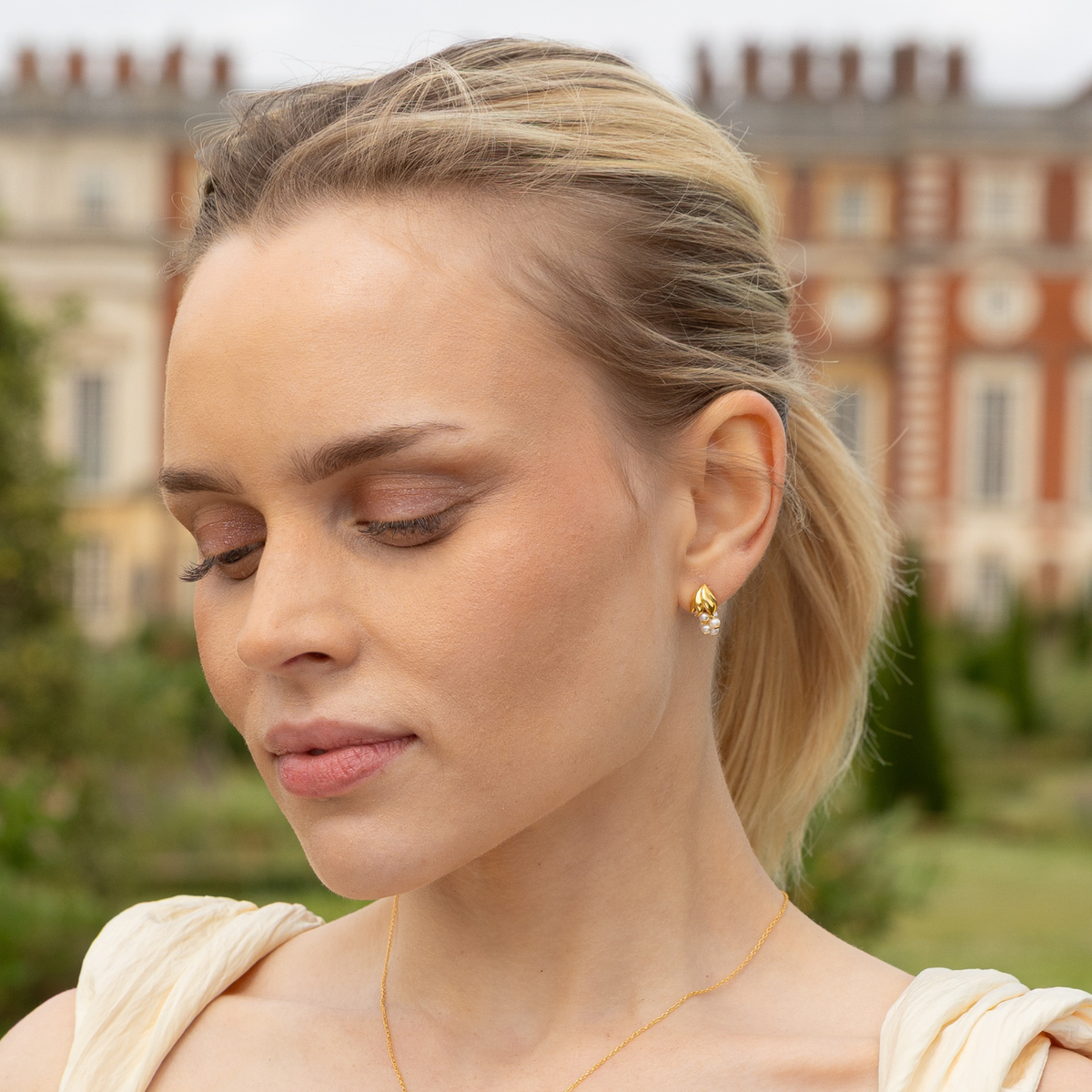 model wearing 18k gold plated sterling silver pearl wisteria earrings