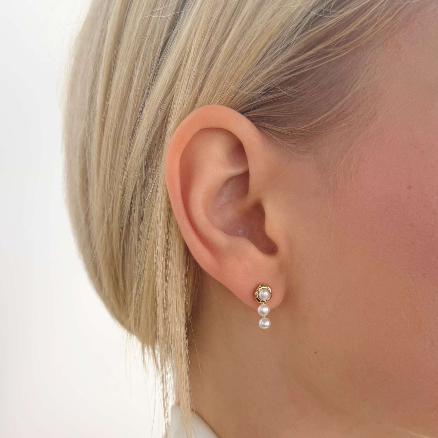 model wearing 18k gold plated 925 sterling silver triple pearl stud earrings