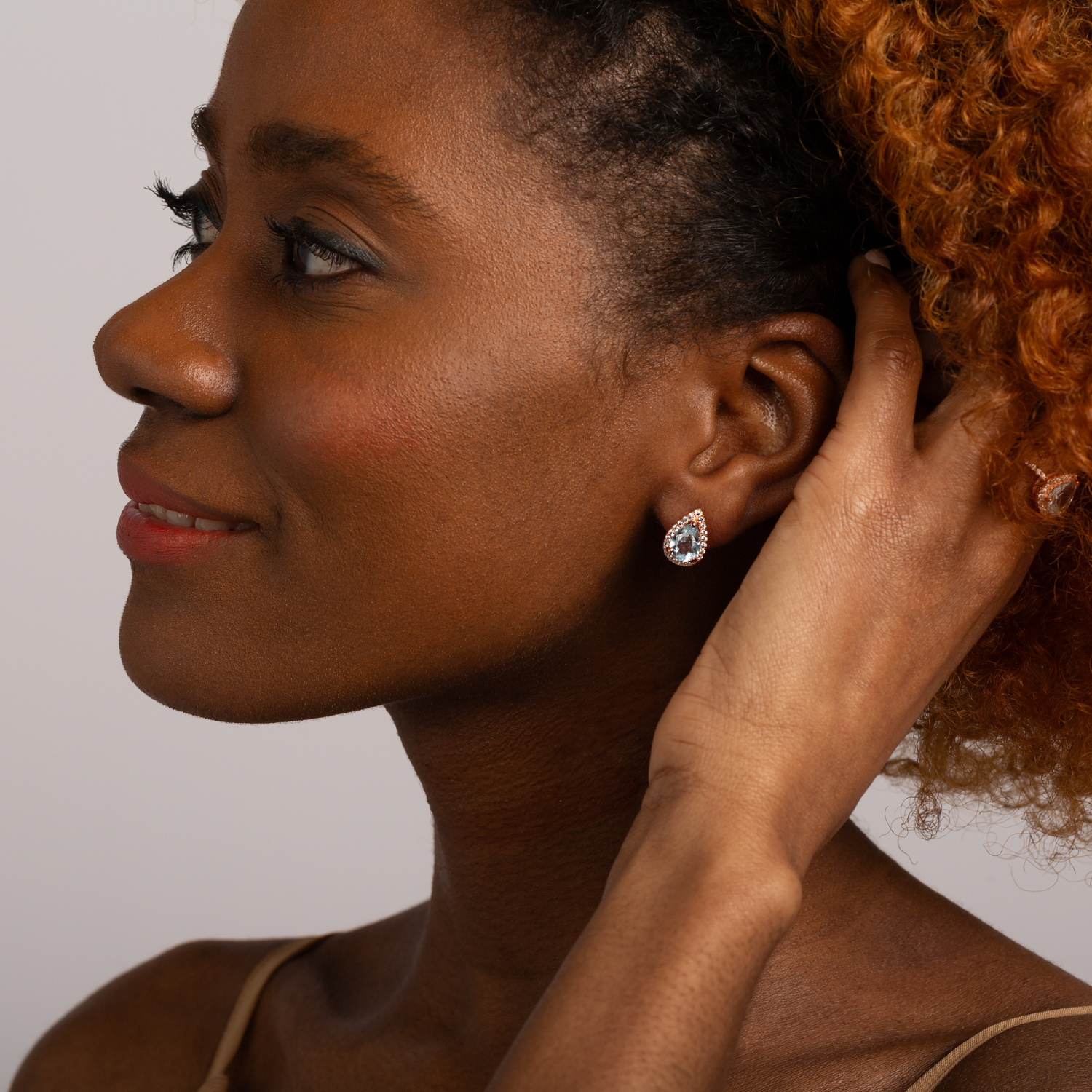 Model wearing 18k rose gold 925 sterling silver pear drop blue topaz stud earrings